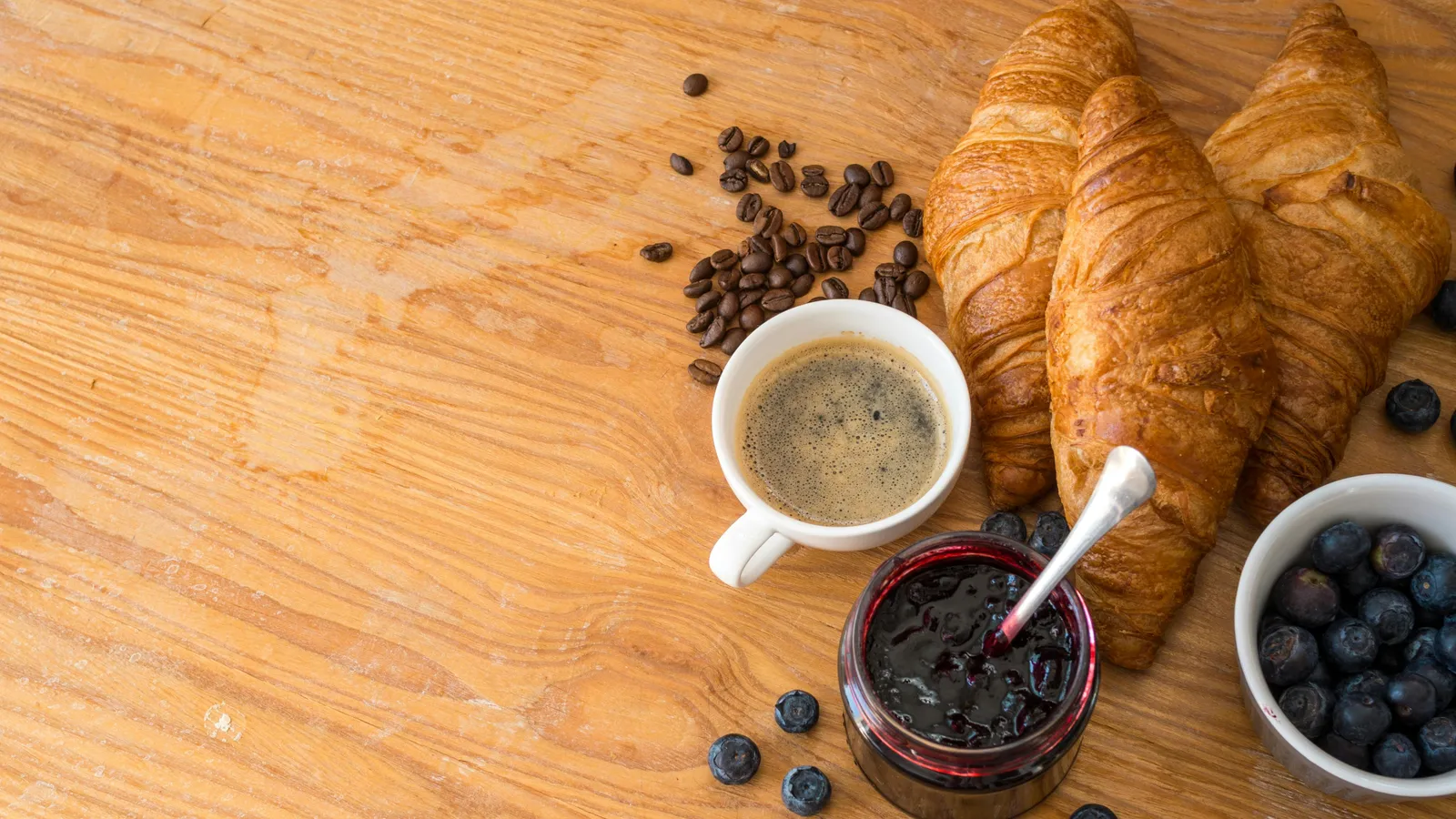 An Italian breakfast spread on a cream tablecloth — espresso cups, fresh cornetti, jam in small dishes, sliced fruit and a bowl of yogurt — laid out for morning service at Hotel Colle Oppio.